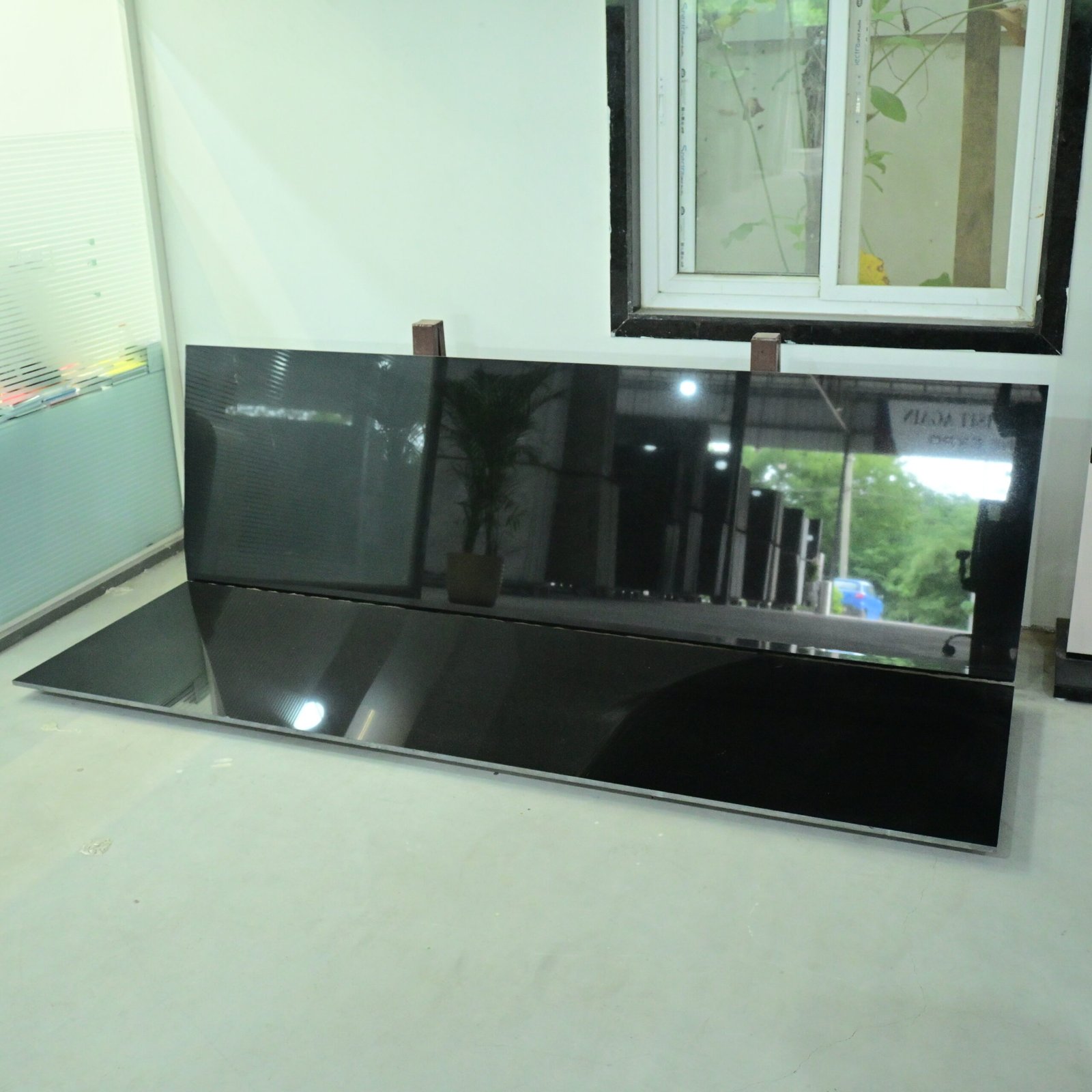 Premium polished Black Granite slab displayed in a granite showroom with a mirror finish.